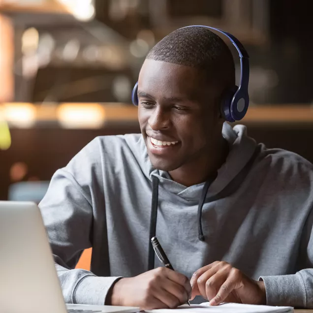 Young Person Studying At A Laptop With Headphones In